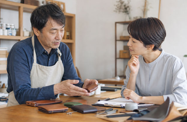 革製品を見ながら商品の特徴やアピールポイントを話し合う二人