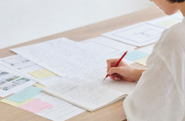 資料や手書きのメモをもとにチラシの原稿を作成する様子